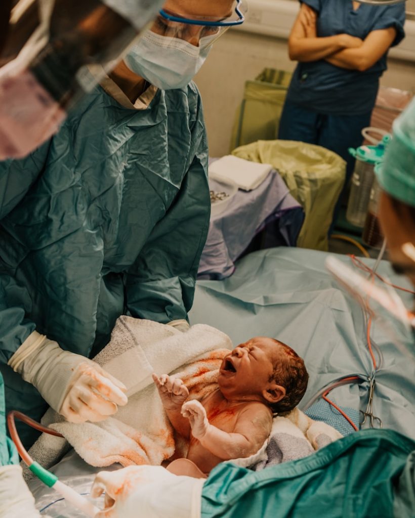 a baby in a hospital bed with medical personnel around him